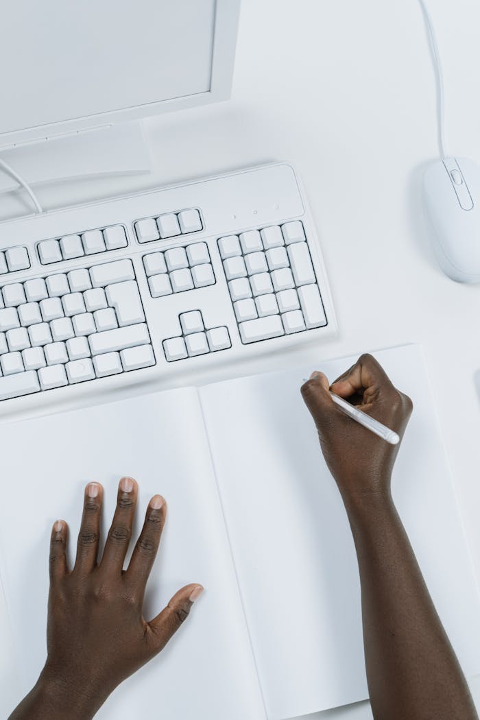 Crafting Captivating Headlines: Your awesome post title goes here Overhead view of hands writing in a notebook at a clean, minimalist workspace with a keyboard and mouse.