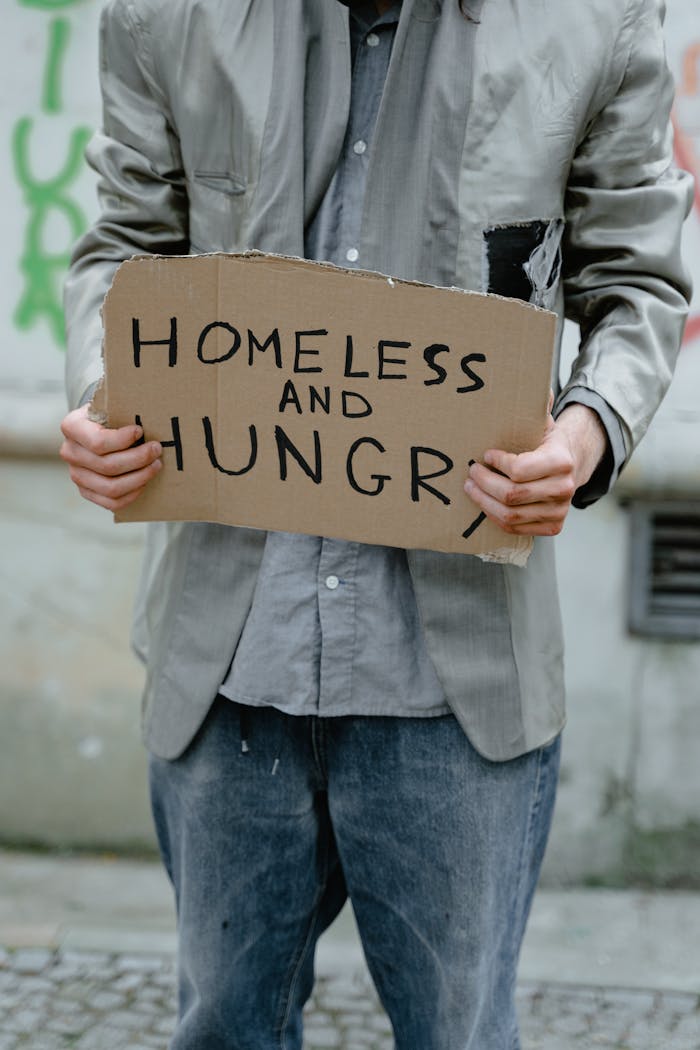 Mastering the First Impression: Your intriguing post title goes here Person holding a 'Homeless and Hungry' sign, depicting urban poverty.